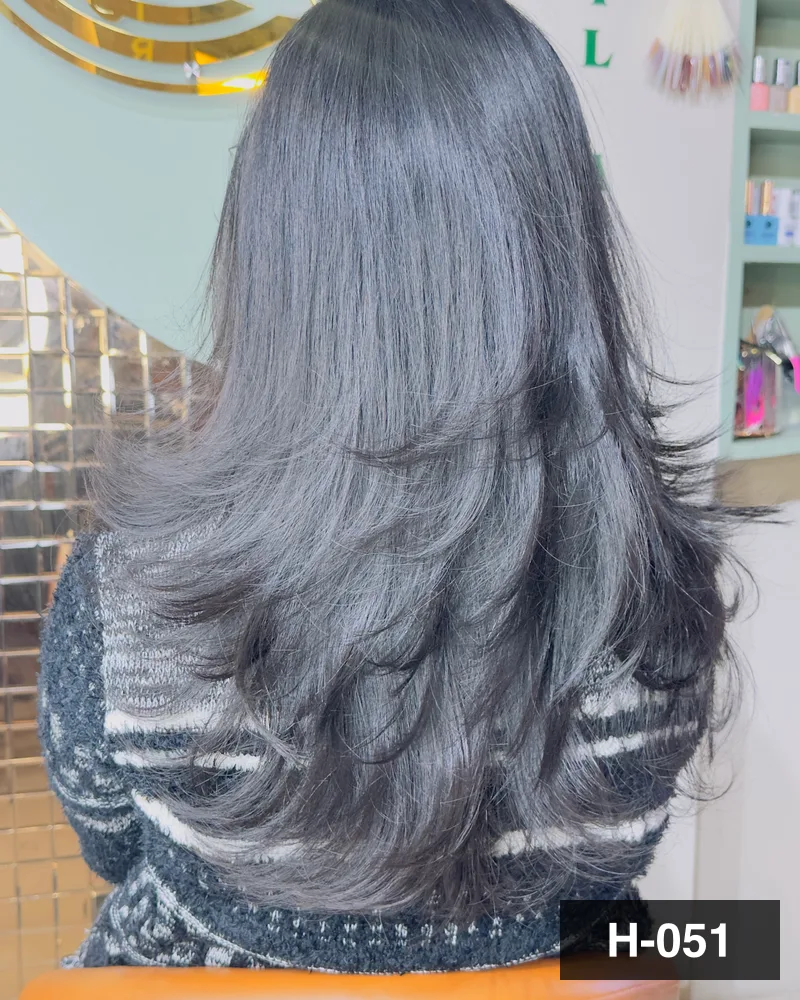 Layered hair blow-dried into soft waves through the mid-lengths and ends, seen from behind at Salon By Babita, Haldwani — reference H-051
