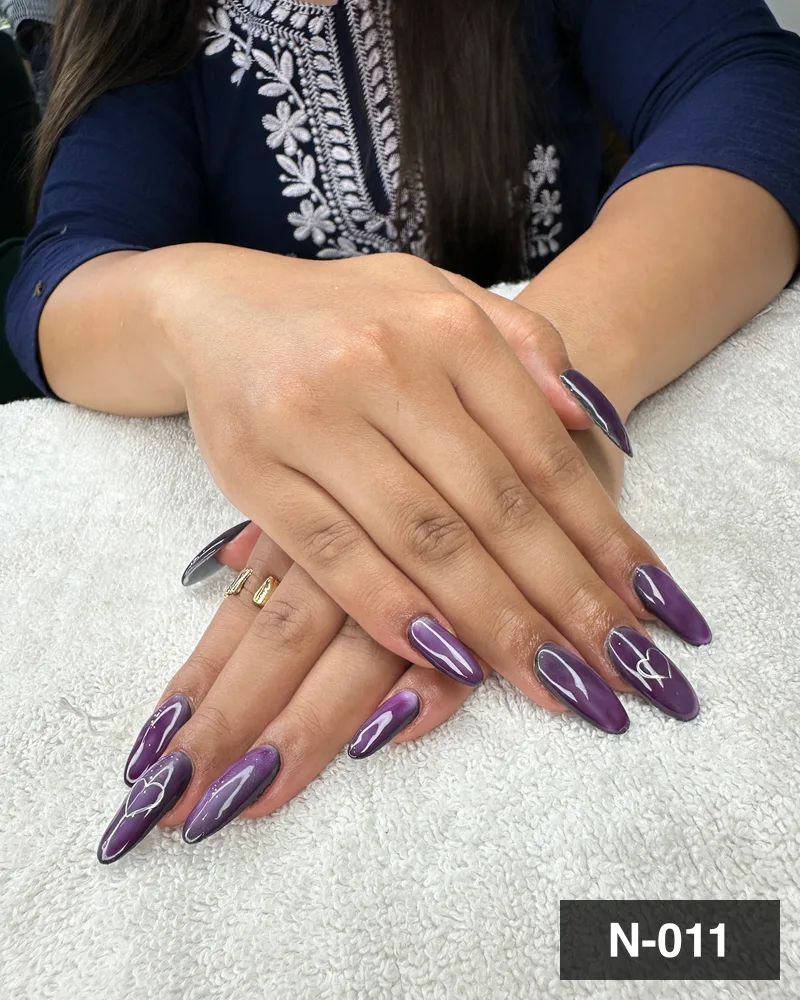 A plum cat-eye almond nail set with freehand white detail at Salon By Babita, Haldwani — reference N-011