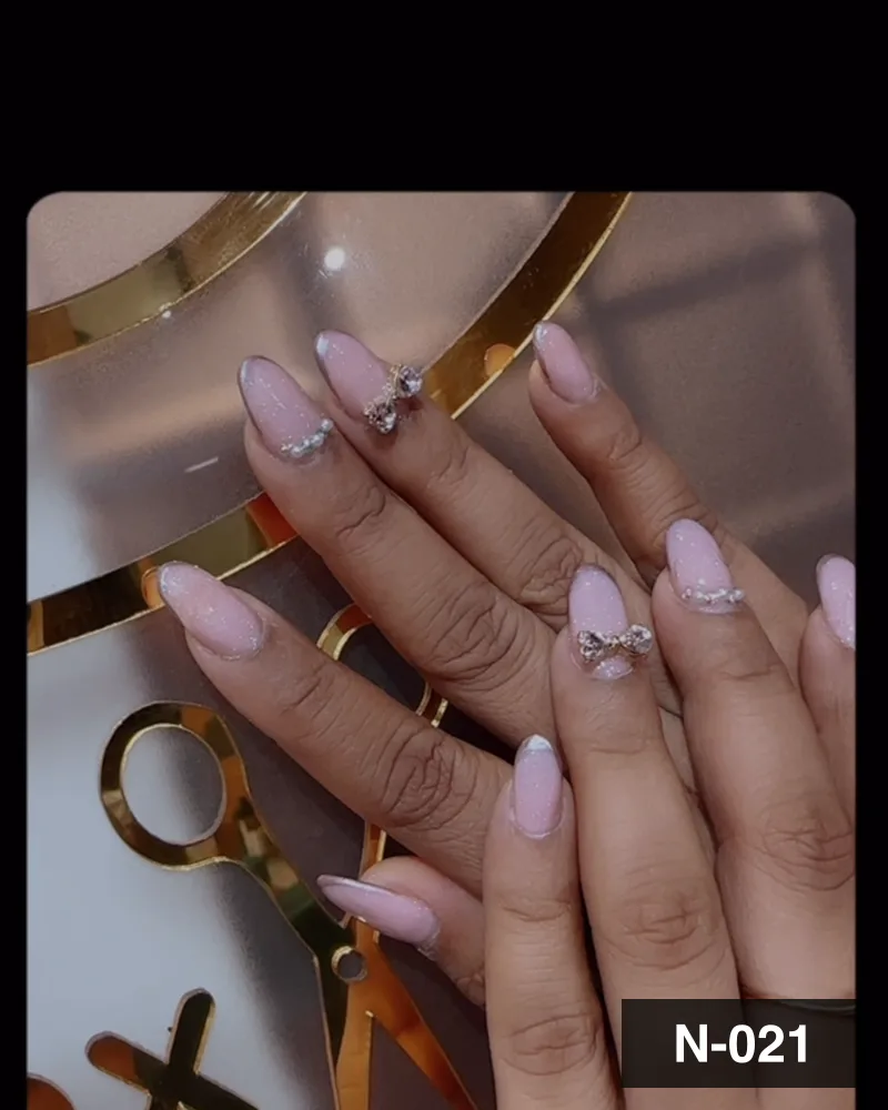 A nude almond set with crystal accents, against the salon's gold monogram at Salon By Babita, Haldwani — reference N-021