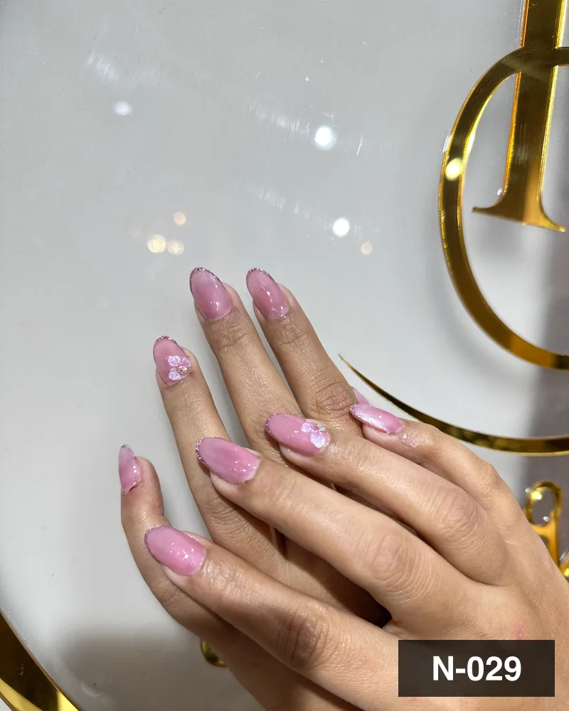 A pale pink almond set with hand-painted white floral detail, against the monogram at Salon By Babita, Haldwani — reference N-029