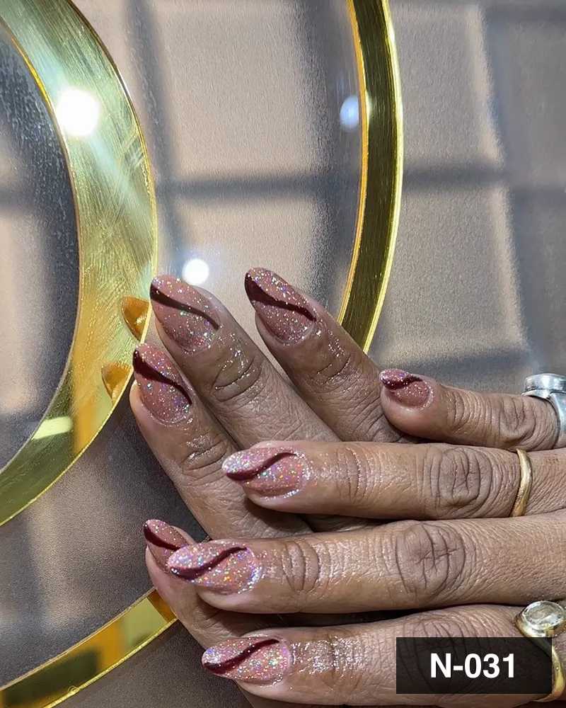 A plum marbled almond set with glitter, photographed against the salon's gold monogram at Salon By Babita, Haldwani — reference N-031