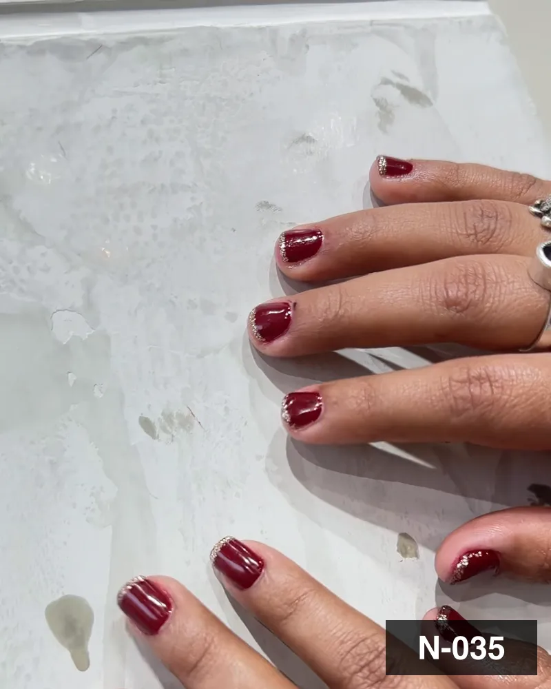 A deep wine almond set, both hands settled on the salon counter at Salon By Babita, Haldwani — reference N-035