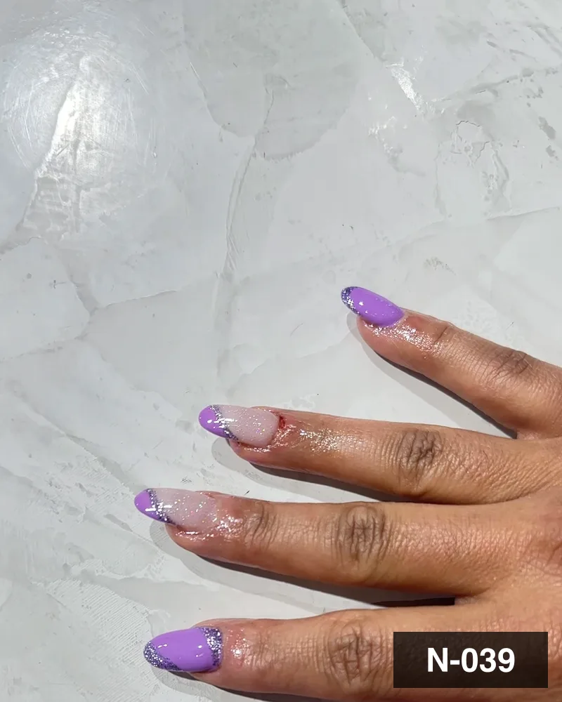 A lilac glitter french almond set, both hands on the salon counter at Salon By Babita, Haldwani — reference N-039