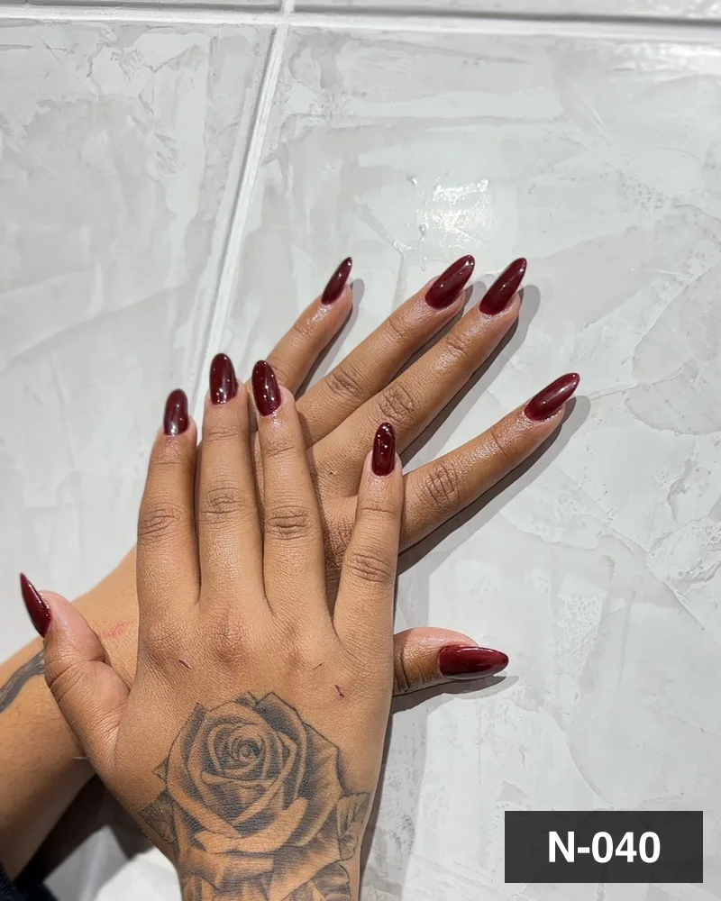 A deep wine almond set, both hands flat on the salon counter at Salon By Babita, Haldwani — reference N-040