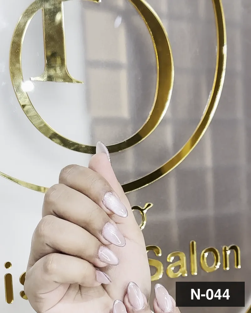 A pale nude almond set, one hand raised against the salon's gold monogram at Salon By Babita, Haldwani — reference N-044