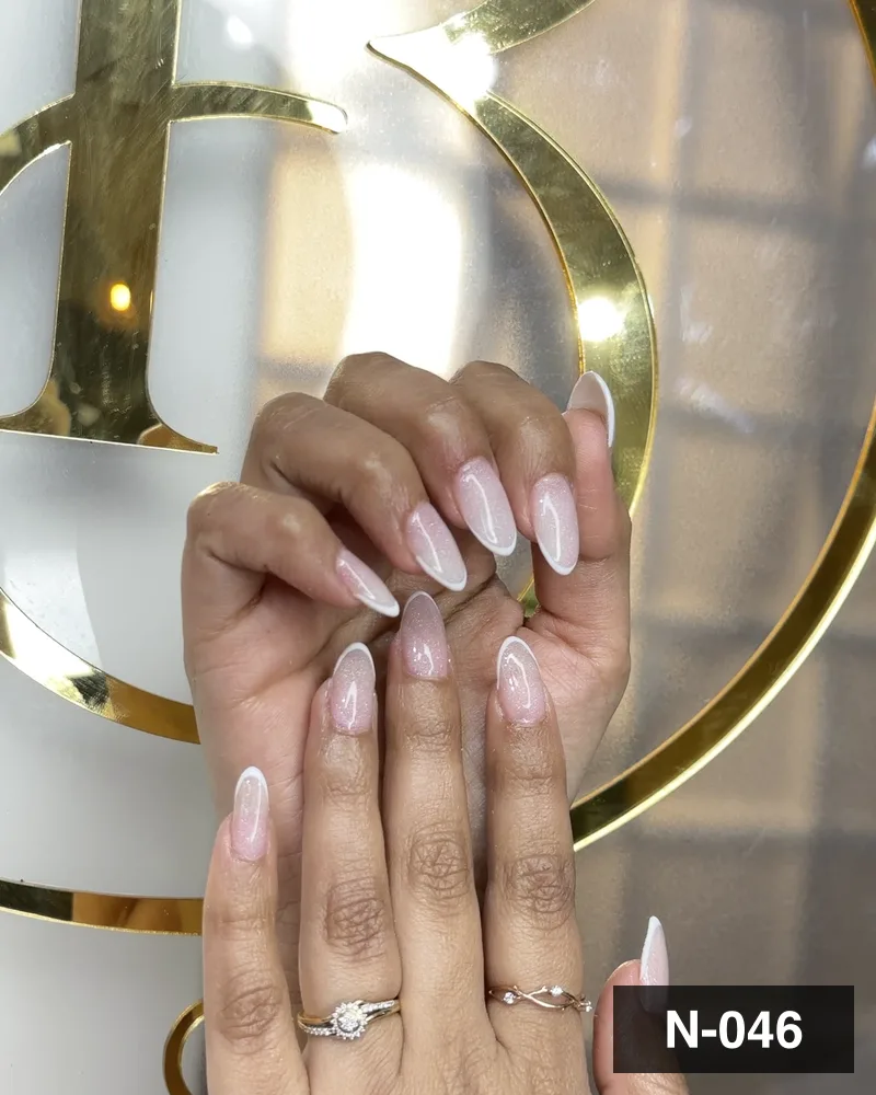 A pearl white almond set, both hands against the salon's gold monogram at Salon By Babita, Haldwani — reference N-046