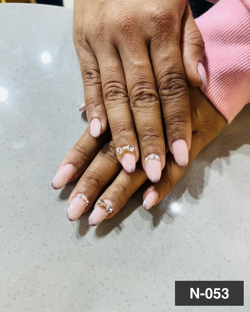 A pale pink almond set with crystal detail, both hands on the salon counter at Salon By Babita, Haldwani — reference N-053