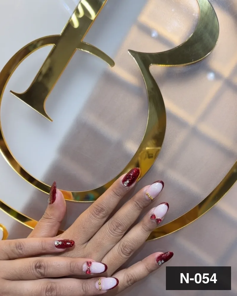 A wine and white freehand set, one hand raised against the salon's gold monogram at Salon By Babita, Haldwani — reference N-054