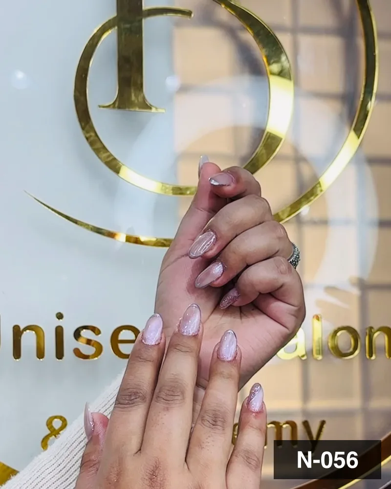 A nude almond set with fine glitter, hands together against the salon's gold monogram at Salon By Babita, Haldwani — reference N-056