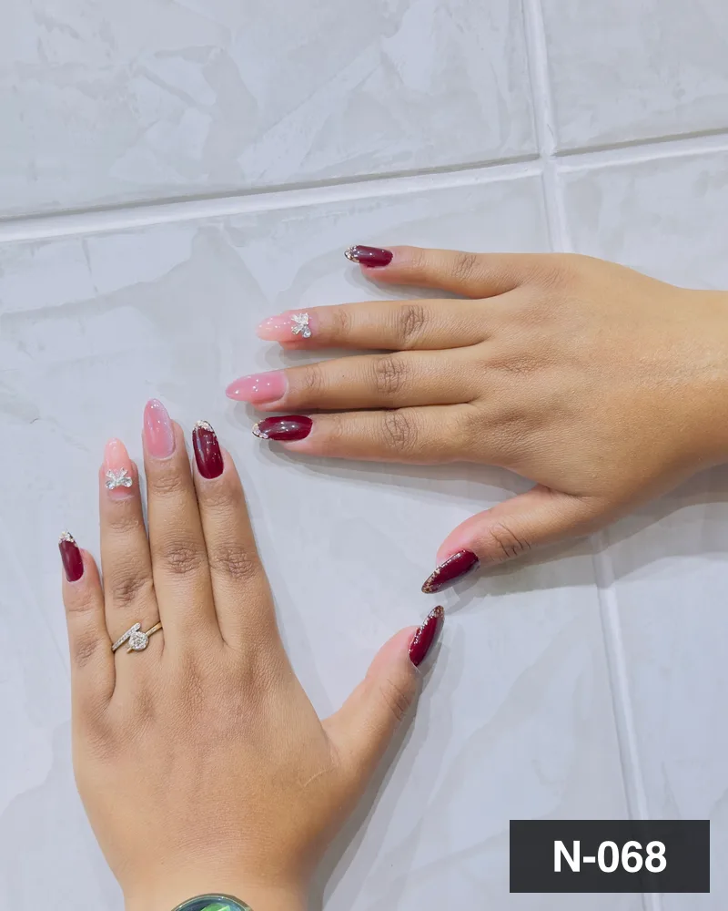 A wine and nude ombré set with a glitter accent nail, both hands on the salon counter at Salon By Babita, Haldwani — reference N-068