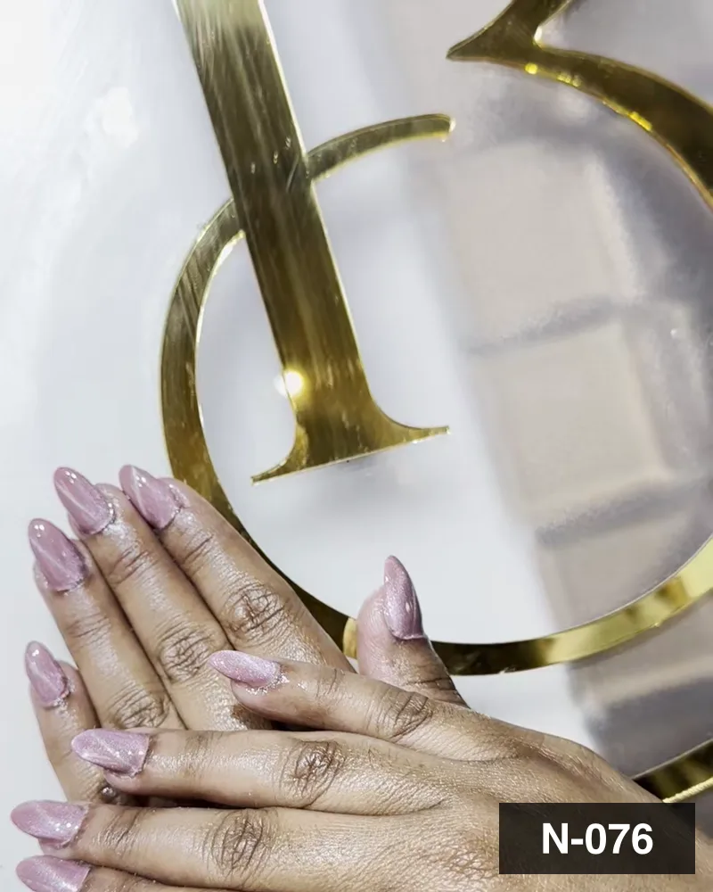 A pale pink long almond set, one hand laid beside the salon's gold monogram at Salon By Babita, Haldwani — reference N-076