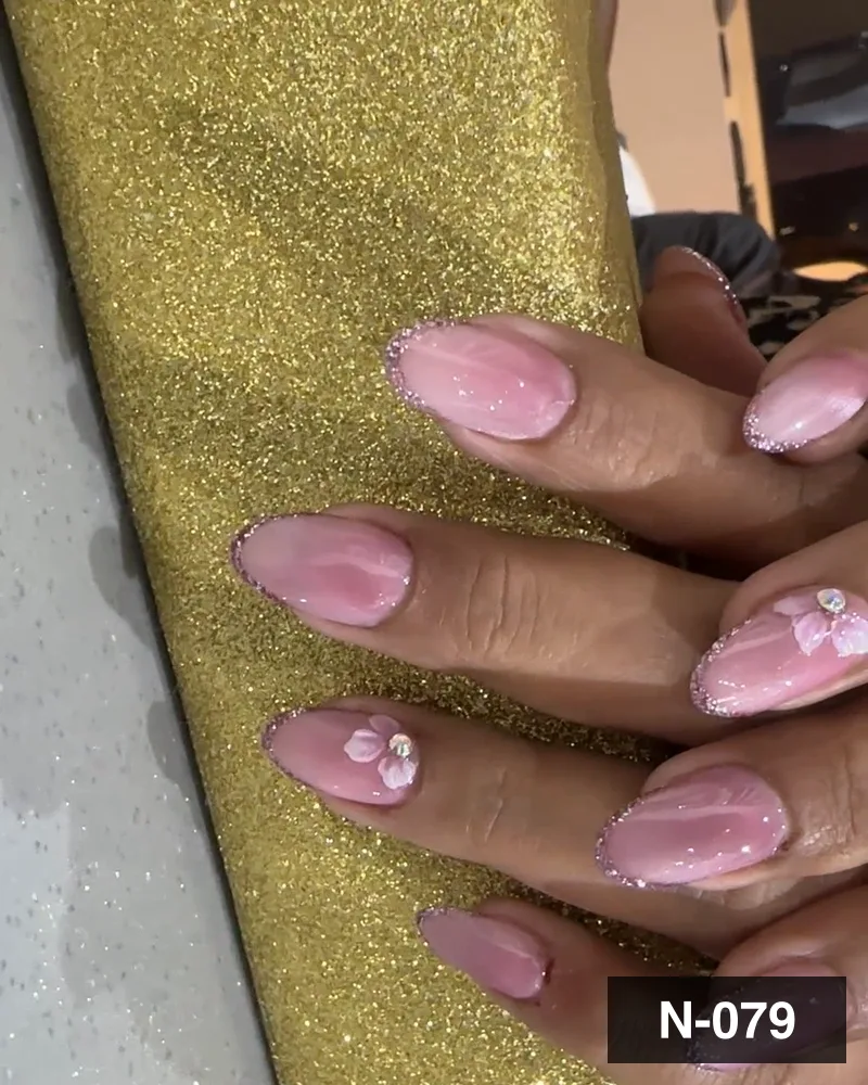 A pink glazed almond set with crystal detail, resting on a gold block at Salon By Babita, Haldwani — reference N-079