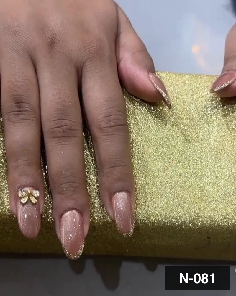A nude almond set with a crystal accent nail, both hands on a gold block at Salon By Babita, Haldwani — reference N-081