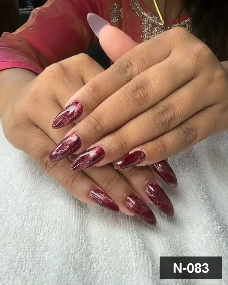 A deep wine glitter cat-eye almond nail set on both hands over a white towel at Salon By Babita, Haldwani — reference N-083