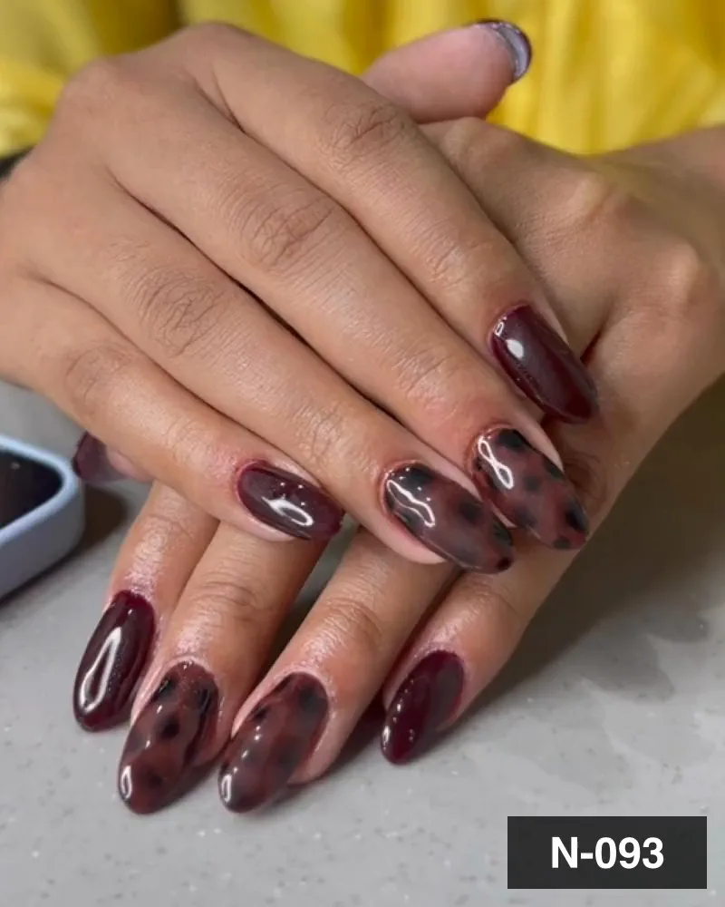 A dark maroon cat-eye almond nail set with leopard spotting on the middle nails, both hands, at Salon By Babita, Haldwani — reference N-093