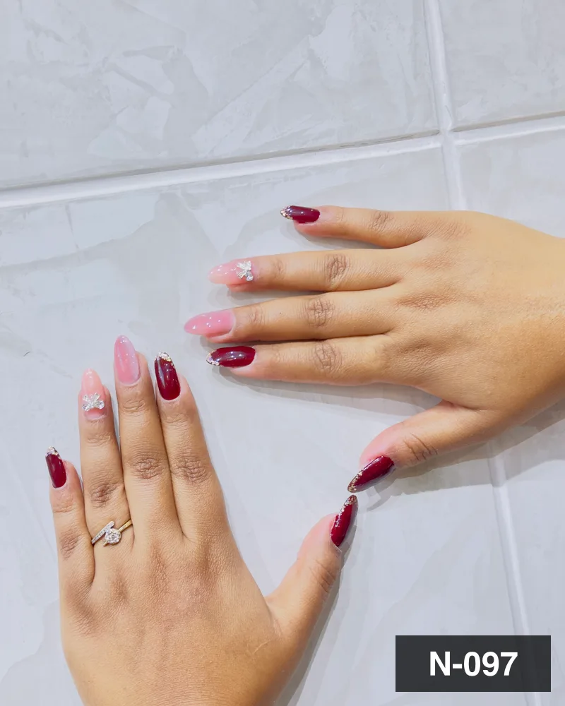 A wine red and pink nail set with raised white bow accents on both hands at Salon By Babita, Haldwani — reference N-097