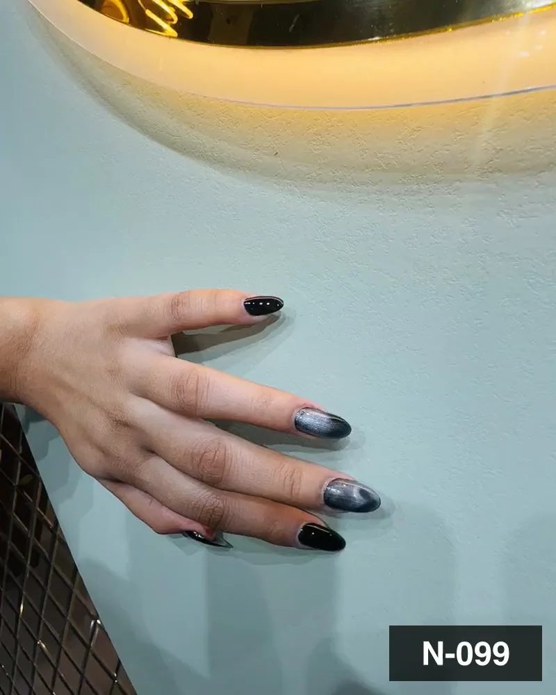 A black and grey cat-eye short almond nail set on one hand against a pale green wall at Salon By Babita, Haldwani — reference N-099