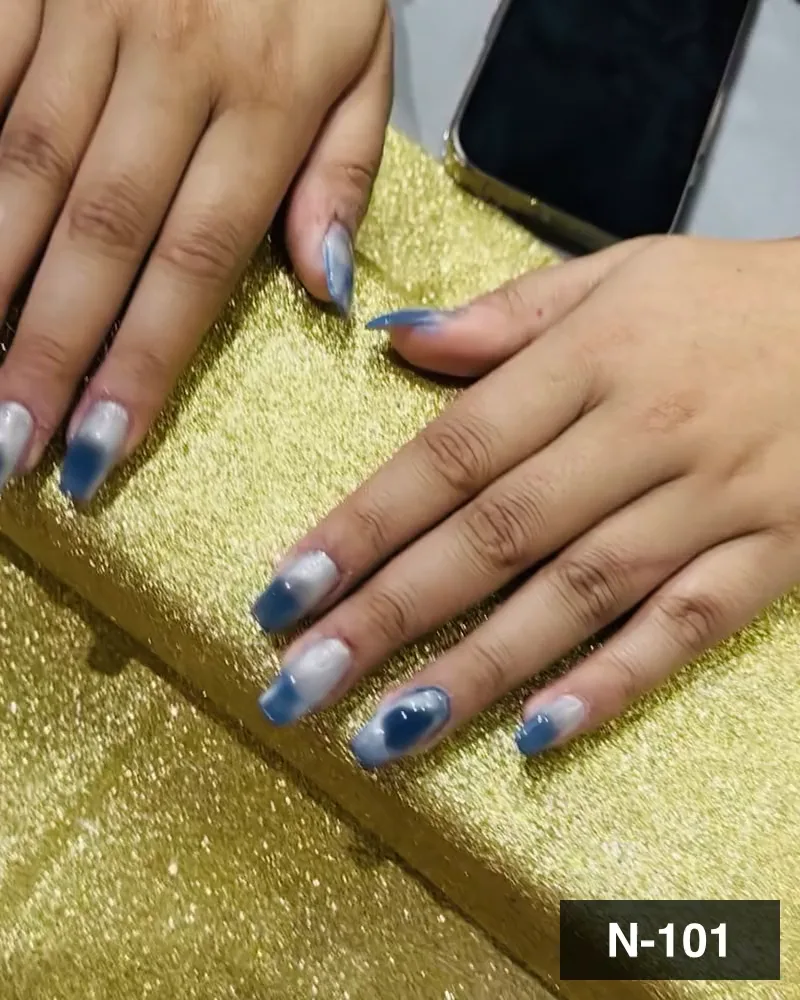 A blue and white ombré marble nail set on one hand resting on a gold block at Salon By Babita, Haldwani — reference N-101