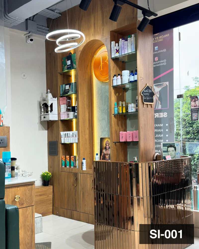 The lit retail product wall and brass screen at the entrance of Salon By Babita, Haldwani — reference SI-001