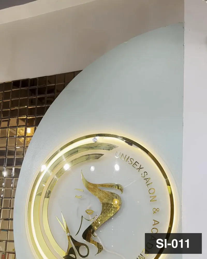 The gilded Unisex Salon and Academy monogram against the mosaic wall at Salon By Babita, Haldwani — reference SI-011