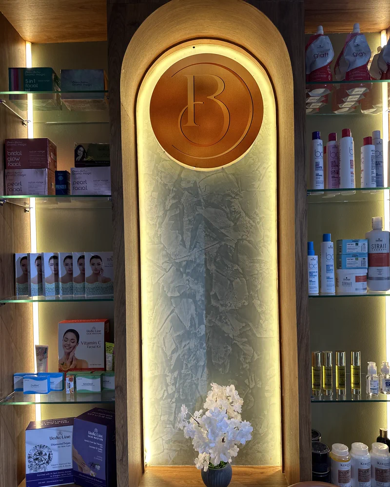 The backlit monogram wall and retail product shelving inside Salon By Babita, Haldwani