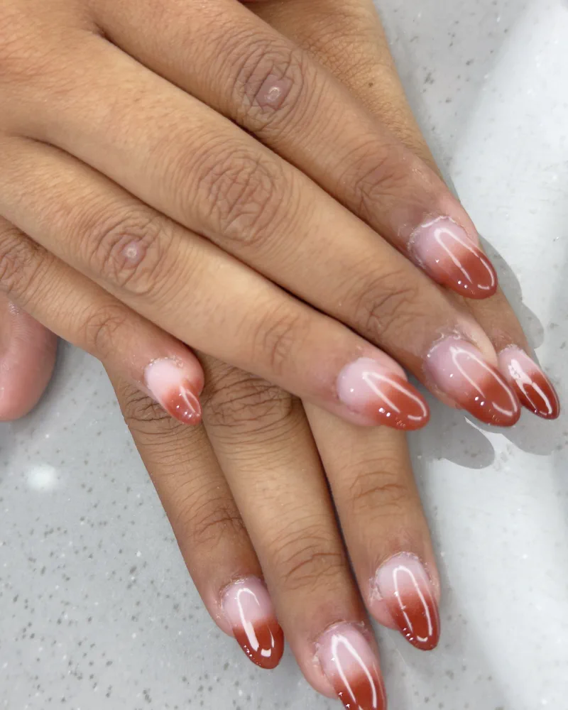 A finished almond nail set in a red and nude ombré at Salon By Babita, Haldwani