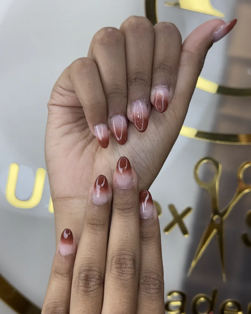 A finished set of long almond nails in a red and nude ombré, photographed at Salon By Babita, Haldwani